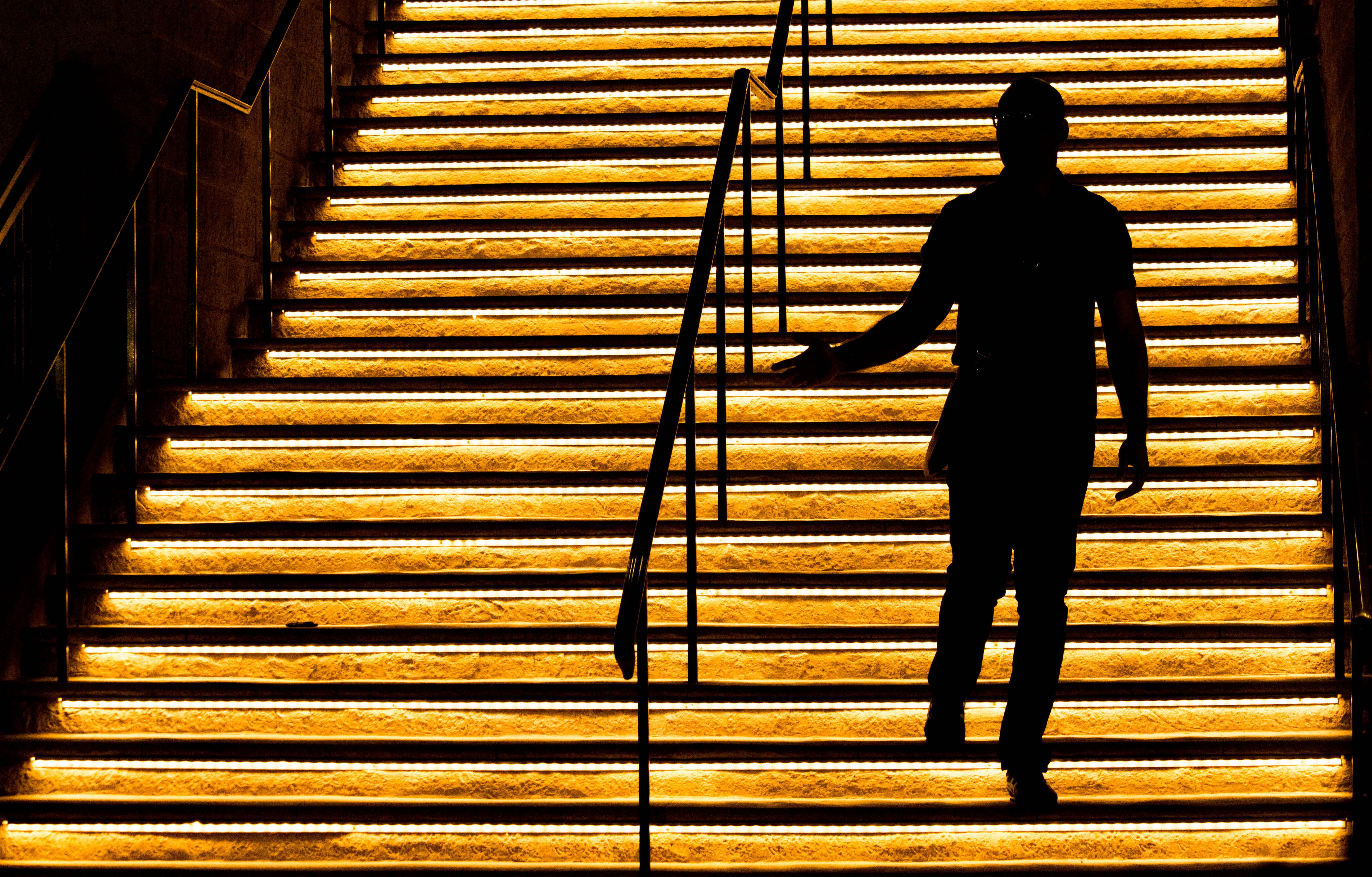 Illuminated stairs with a person in shadow walking up the stairs